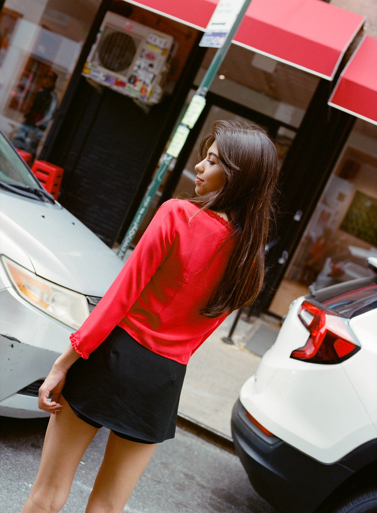 Back view of the Mila Top in Cherry with a black mini skirt on a city street
