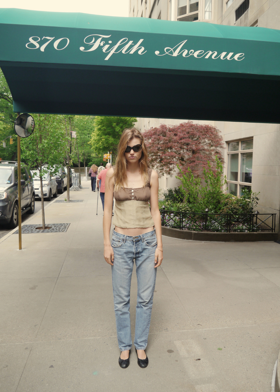 Woman standing on a sidewalk under a '870 Fifth Avenue' awning.