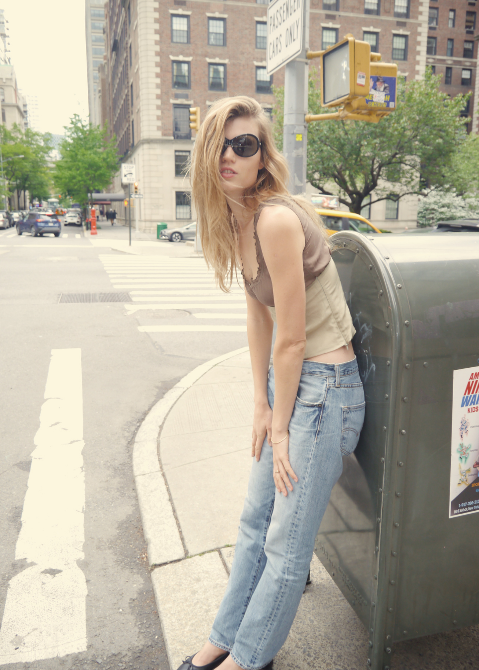 Woman leaning against a mailbox on a city street