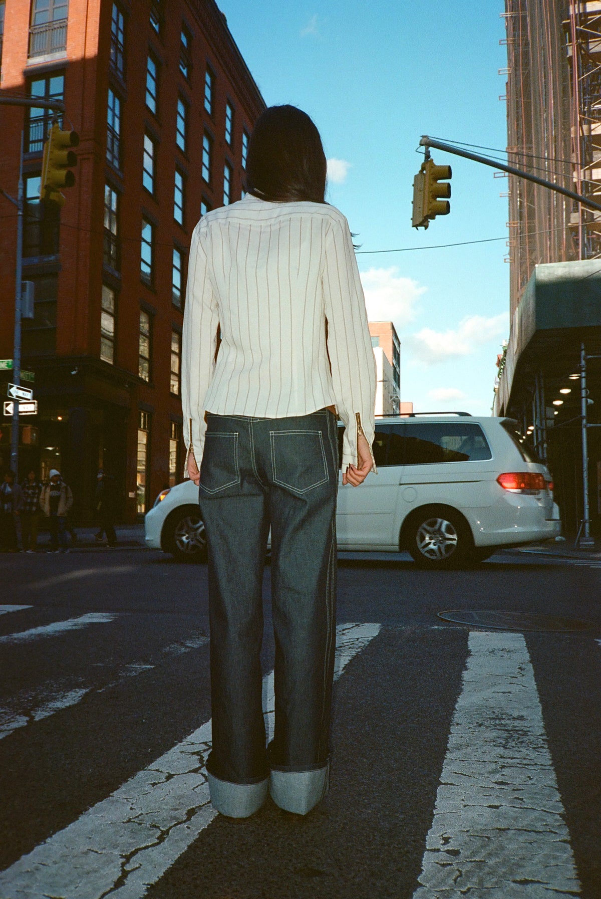 Back view of the Louie Shirt in Cream with dark wide-leg jeans on a city street