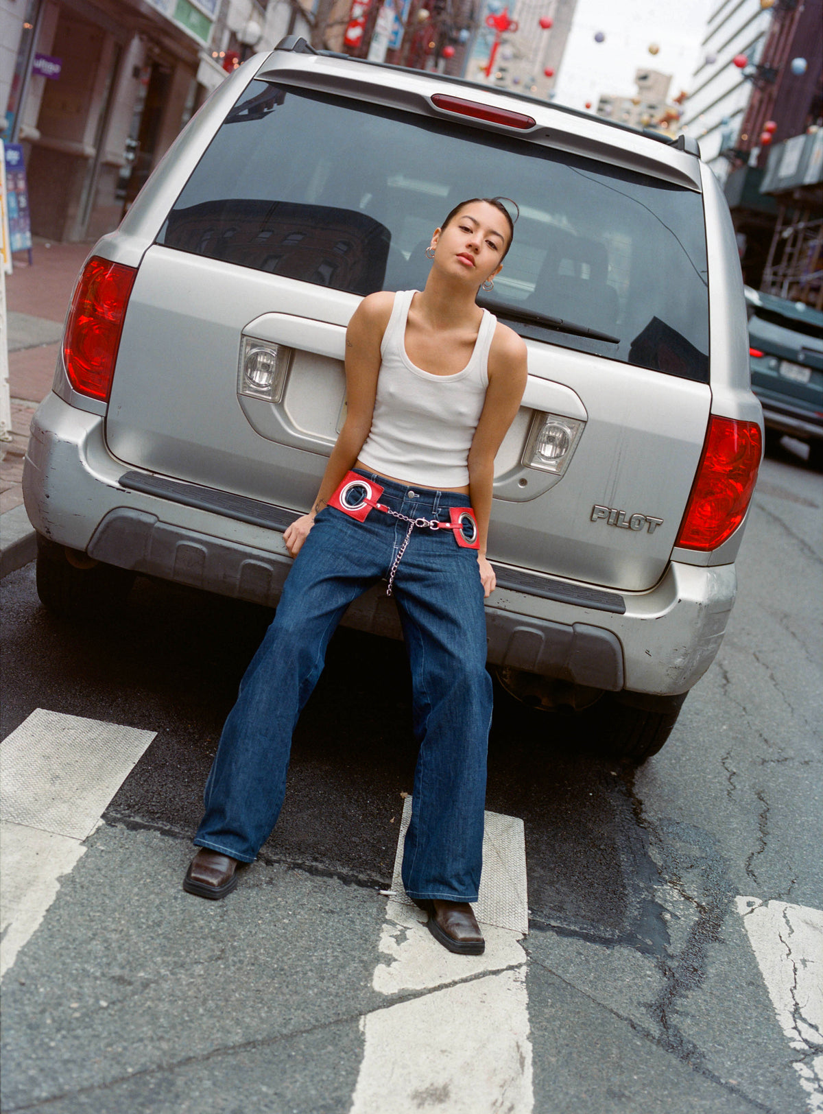 Model in the Lottie Jean in Indigo leaning against the back of a silver car
