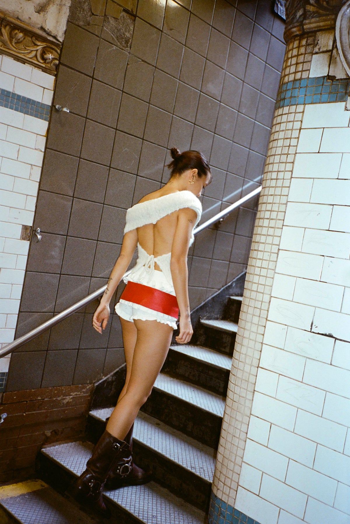 Back view of the Bella Belt in Ruby worn with a white knit set on subway stairs